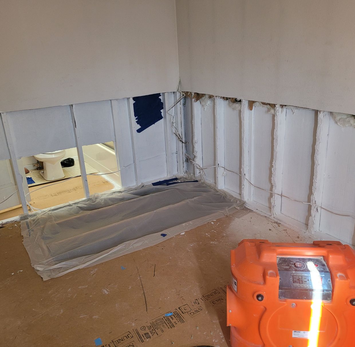 Flood-cut drywall and containment sheeting with an air mover running during water damage remediation